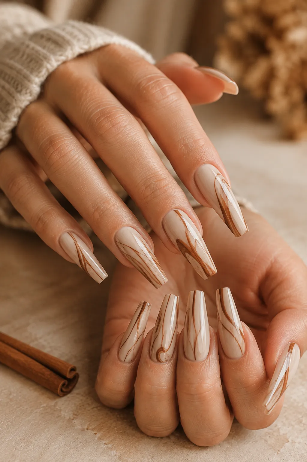Long coffin nails with a warm cream and caramel base featuring delicate deep cinnamon-brown line art inspired by cinnamon sticks.