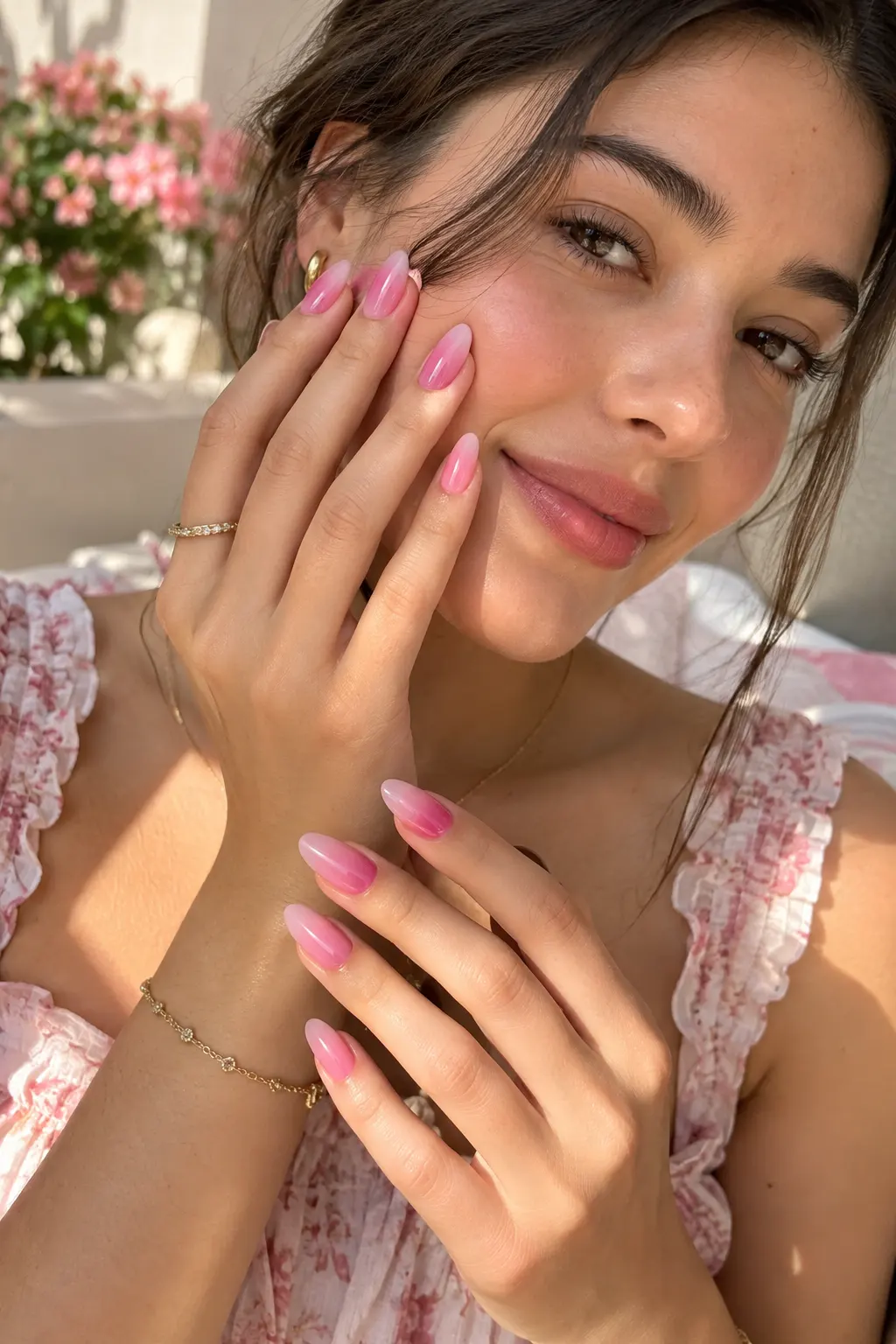 Cute summer manicure featuring glossy almond-shaped nails with a smooth strawberry pink to sheer blush pink candy floss ombré gradient, photographed on a stylish woman.