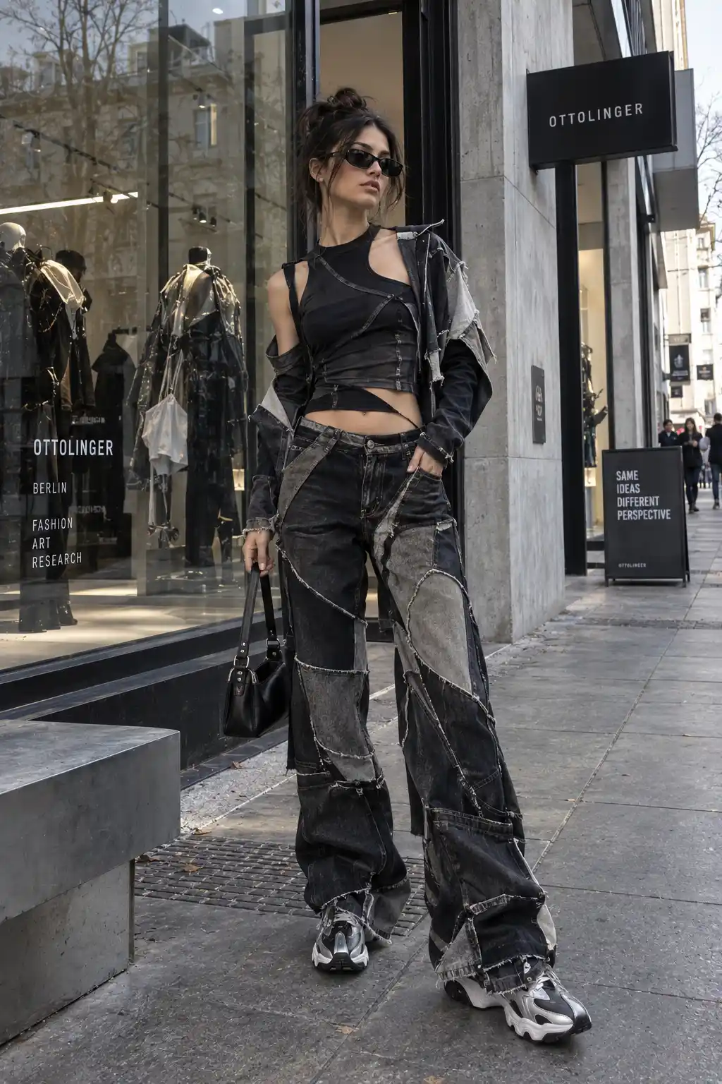 Ottolinger-inspired women's avant-garde streetwear outfit with an asymmetrical black top, deconstructed jacket, reconstructed dark denim, sculptural sneakers, and a modern Berlin fashion boutique.