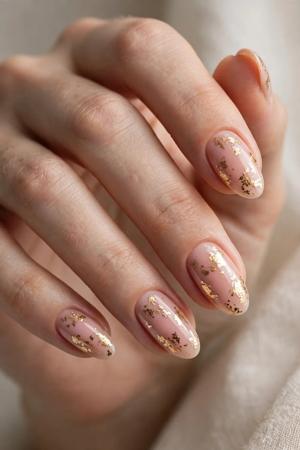 Blush nude New Years Eve nails decorated with irregular gold foil flakes