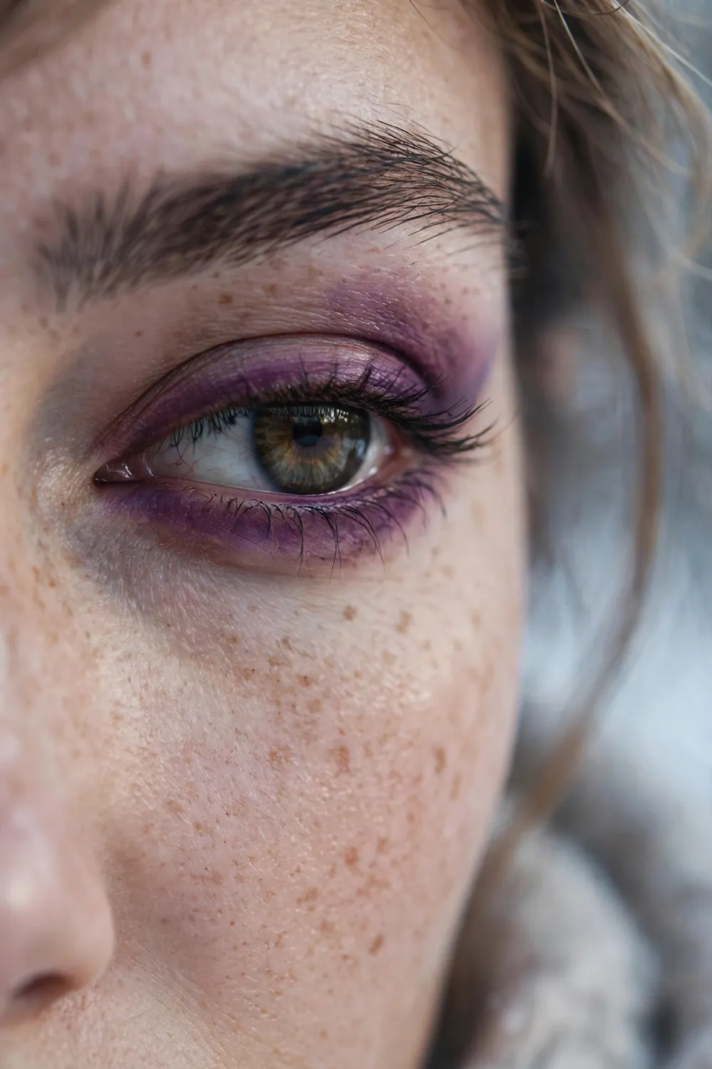 Plum coloured smudged eyeliner softly blended around the eye