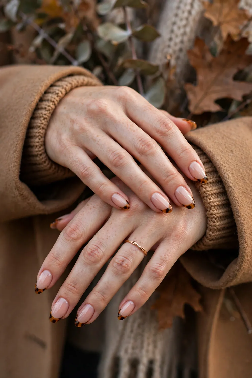 Close up of hands with nude nails and amber tortoiseshell french tips