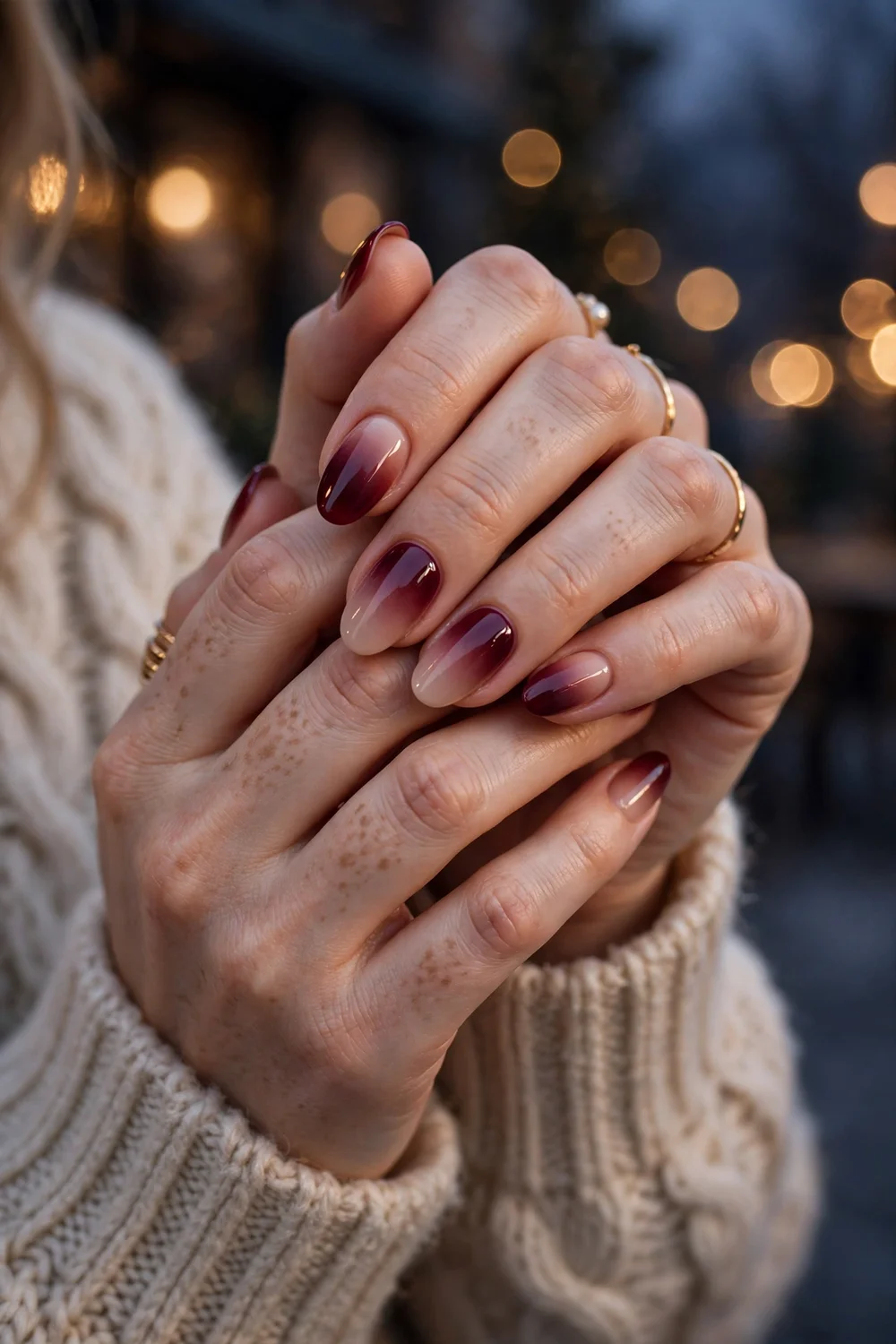 Close up of hands with wine red to nude ombre nails in an elegant winter evening look