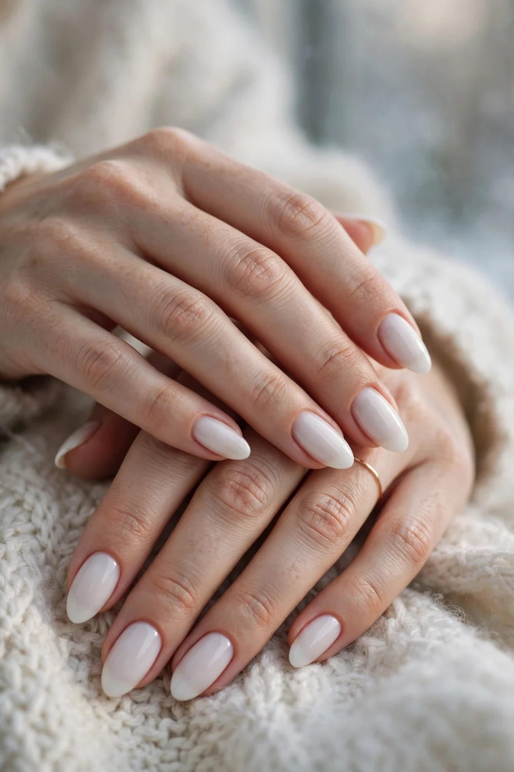 Close up of hands with milky white almond nails in soft winter light